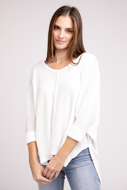 Model wearing a white 3/4 sleeve V-neck hi-low hem jacquard sweater paired with jeans.