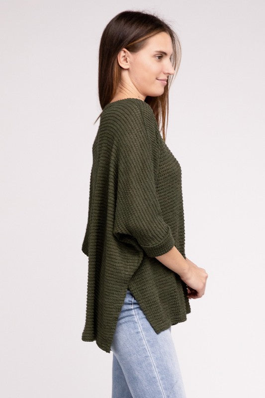 Side view of a model wearing an olive green 3/4 sleeve jacquard sweater with a hi-low hem.