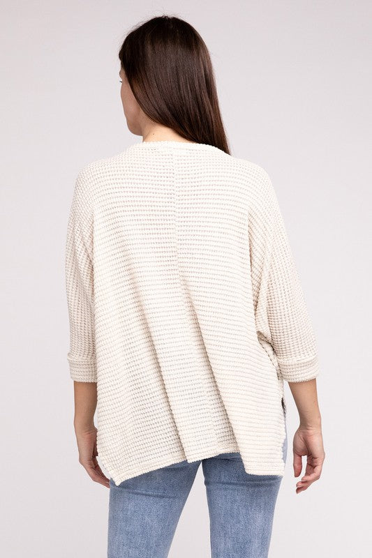 Back view of a woman wearing a cream-colored 3/4 sleeve sweater with a hi-low hem and relaxed fit.