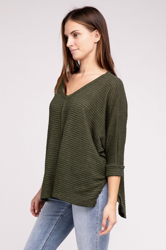 Model wearing a 3/4 sleeve V-neck hi-low hem jacquard sweater in olive green with jeans.