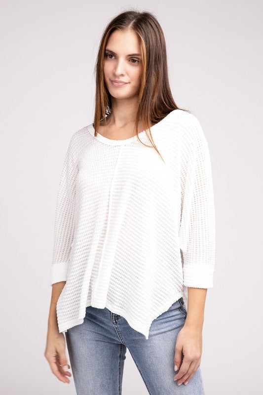 Model wearing a white 3/4 sleeve v-neck hi-low hem jacquard sweater, styled with jeans.