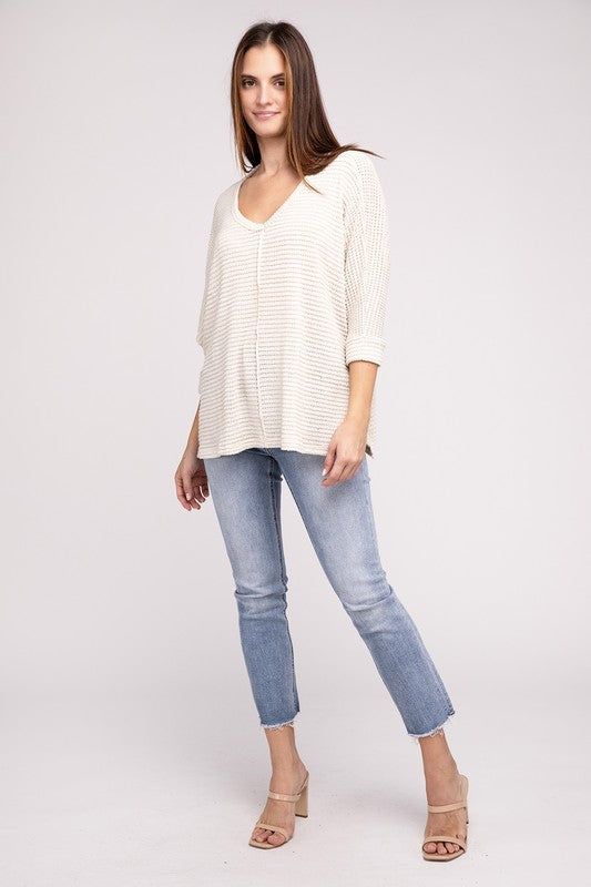 Model wearing a 3/4 Sleeve V-Neck Hi-Low Hem Jacquard Sweater with jeans and sandals, showcasing a casual chic look.