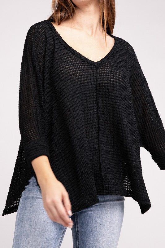 Model wearing a black 3/4 sleeve V-neck hi-low hem jacquard sweater, showcasing its relaxed fit and style.