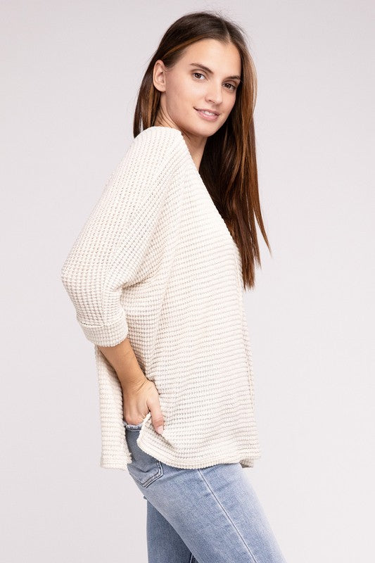 Model wearing a casual 3/4 sleeve V-neck jacquard sweater in cream, styled with blue jeans.