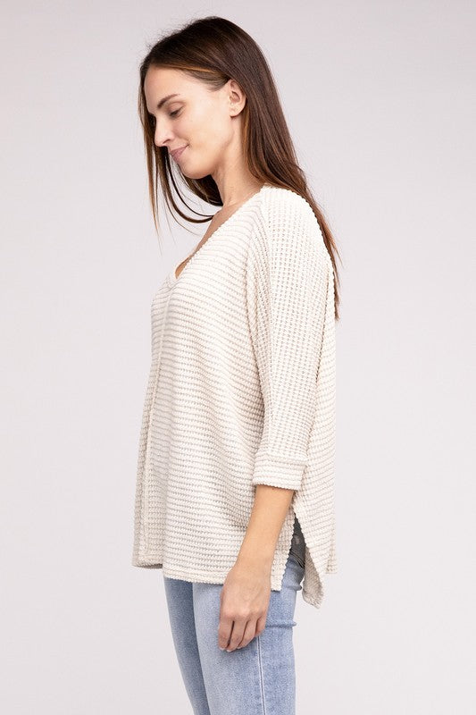 Model wearing a 3/4 sleeve v-neck hi-low hem jacquard sweater in light cream, styled with denim jeans.