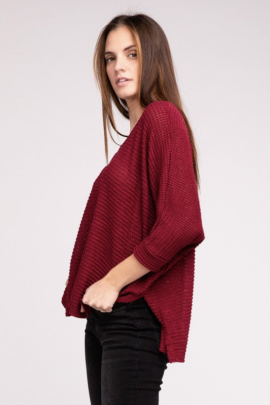 Model wearing a burgundy 3/4 sleeve V-neck hi-low hem sweater, styled with black jeans.