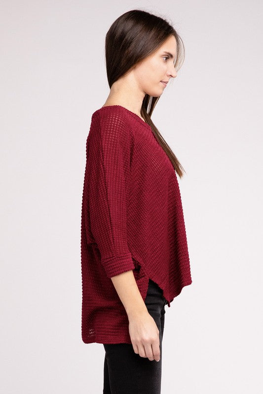 Side view of a model wearing a burgundy 3/4 sleeve V-neck hi-low hem jacquard sweater.