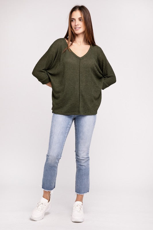 Model wearing a casual green 3/4 sleeve V-neck sweater with a relaxed fit and jeans.