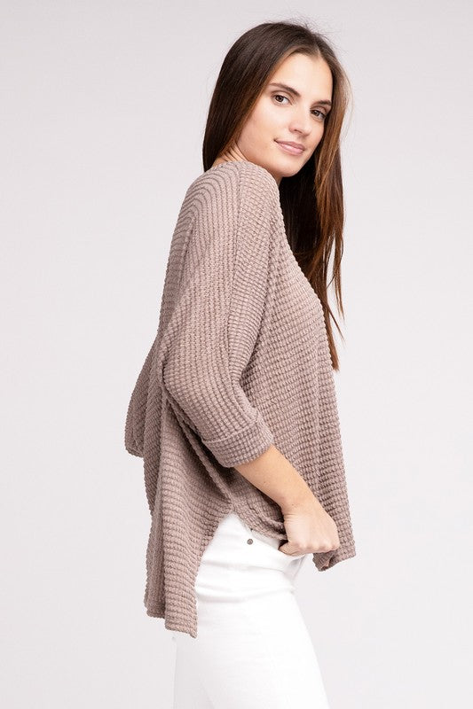 Model wearing a casual 3/4 sleeve jacquard sweater with a hi-low hem, styled with white jeans.