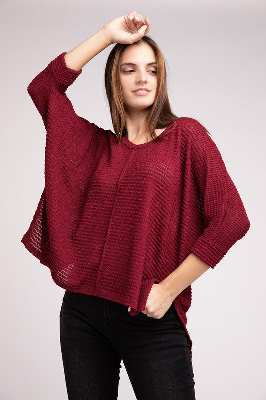 Model wearing a burgundy 3/4 sleeve jacquard sweater with a hi-low hem, styled casually with black jeans.