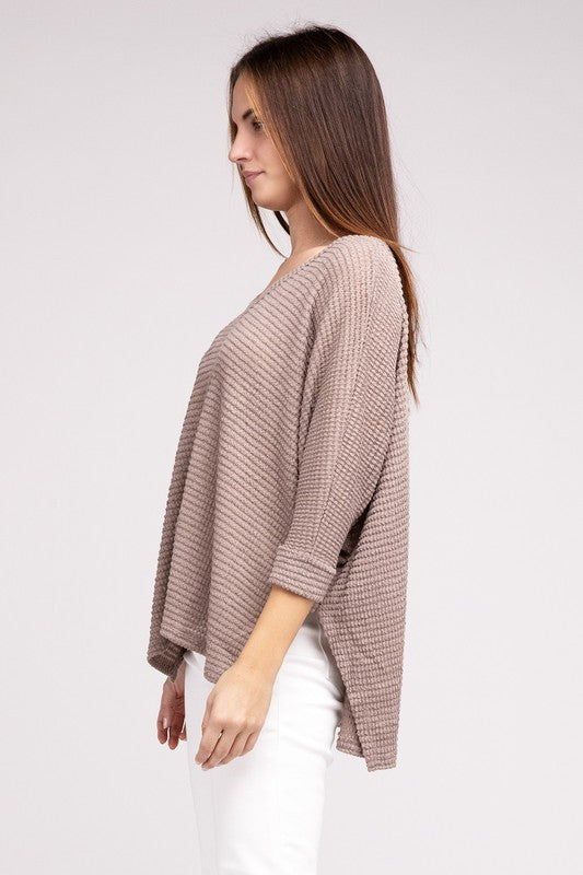Side view of a woman wearing a beige 3/4 sleeve V-neck hi-low hem jacquard sweater with casual fit.