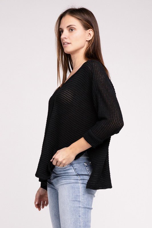 Model showcasing a black 3/4 sleeve V-neck sweater, featuring a hi-low hem and stylish design.