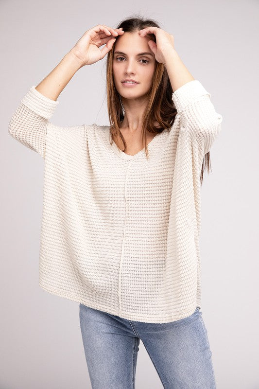 Model wearing a 3/4 Sleeve V-Neck Jacquard Hi-Low Hem Sweater in cream color, styled with jeans.