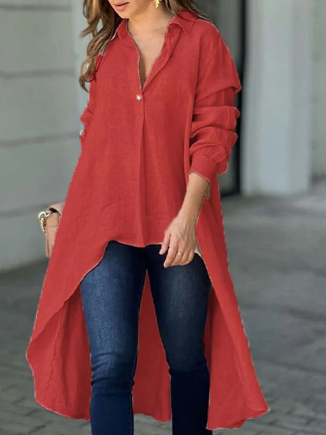 Woman wearing a full-size high-low collared neck long sleeve red shirt paired with blue jeans.