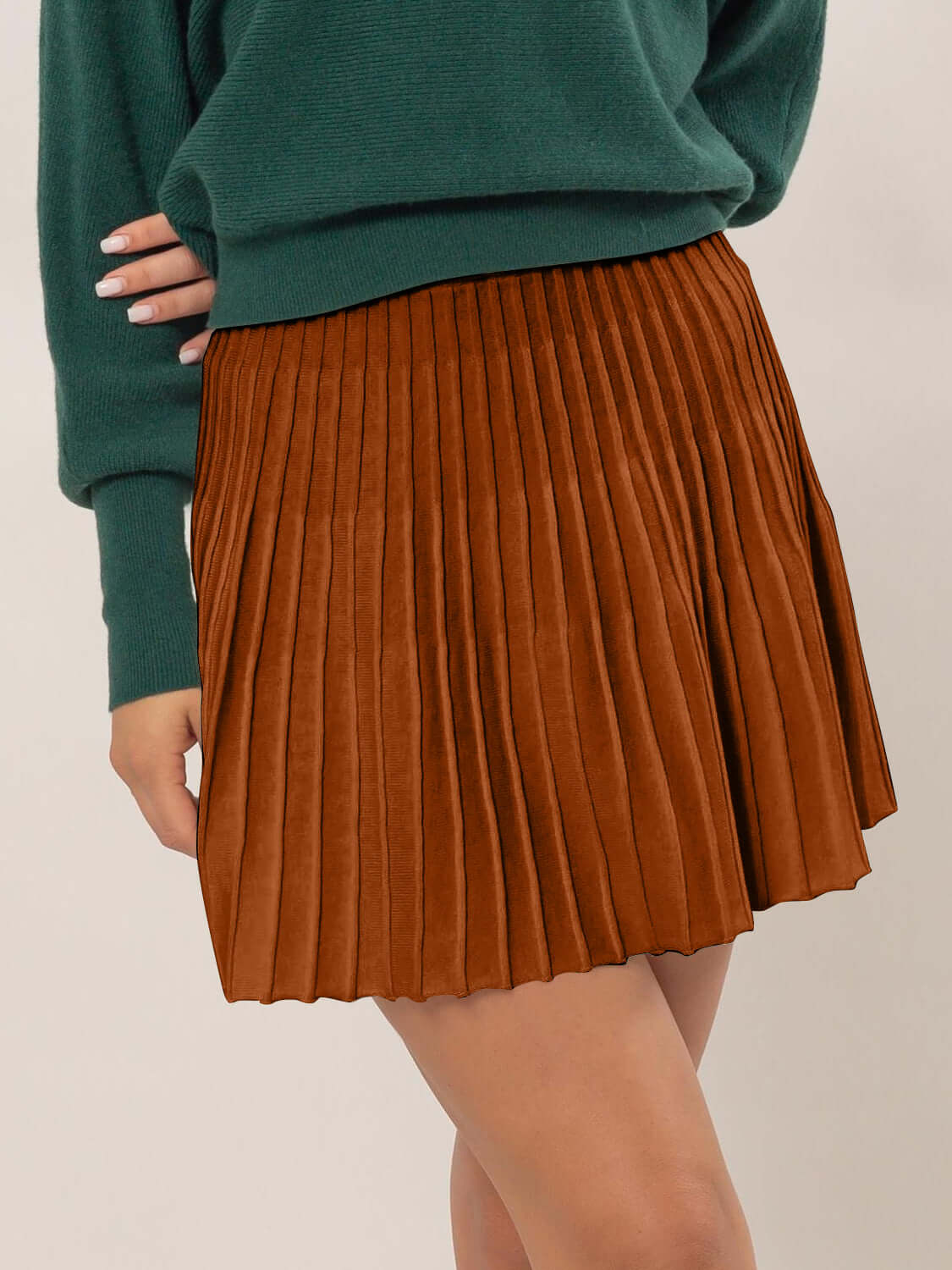 Woman wearing HYFVE high waist knit pleated flare mini skirt in brown, paired with a green sweater.