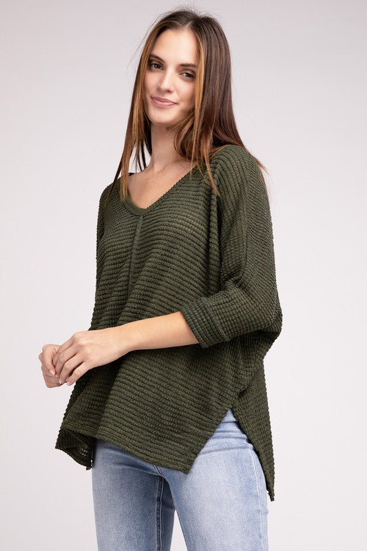 Model wearing a 3/4 sleeve V-neck hi-low hem jacquard sweater in olive green with stylish casual fit.