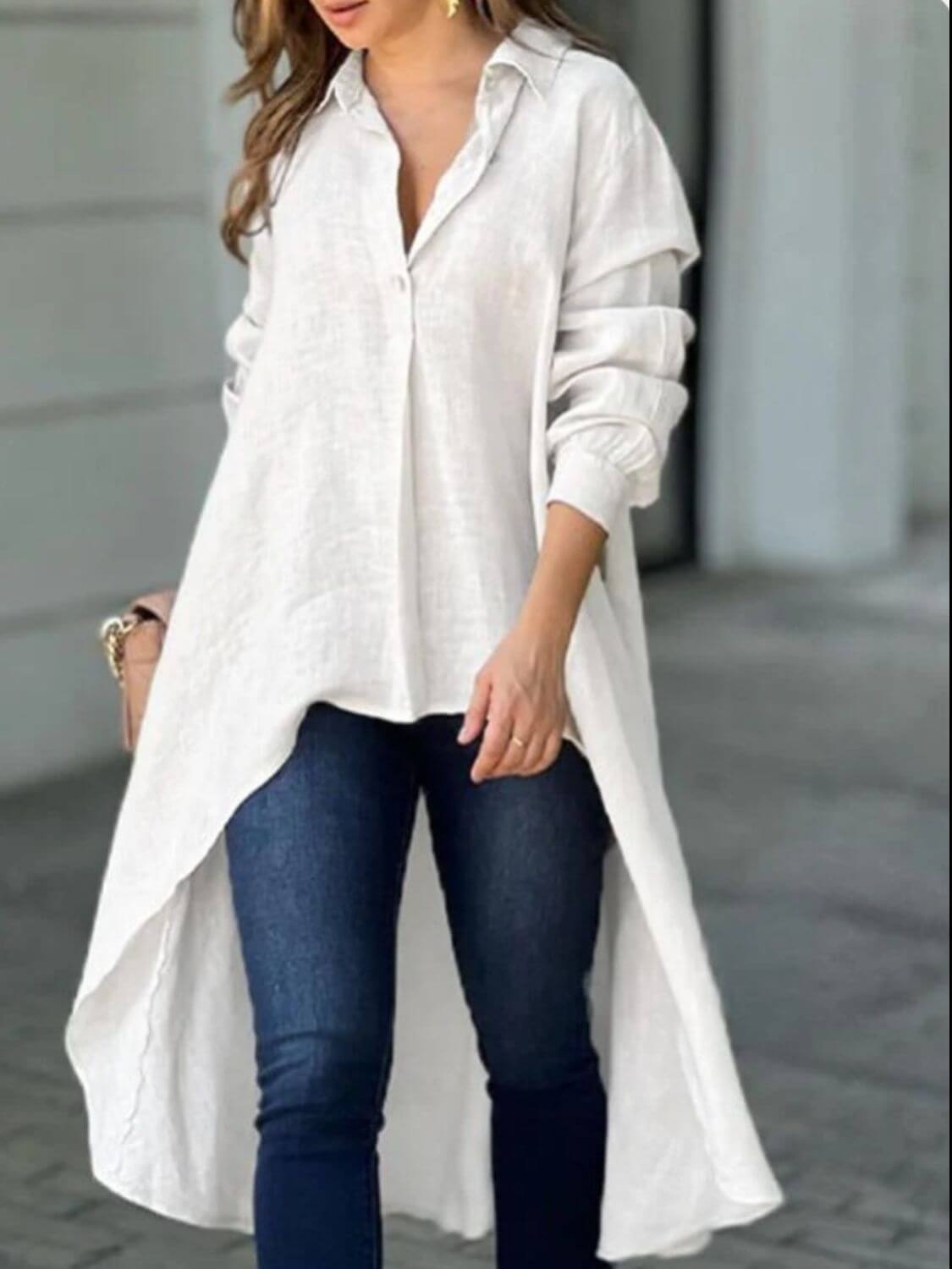 Woman wearing a full size high-low collared neck long sleeve shirt in white, paired with blue jeans.